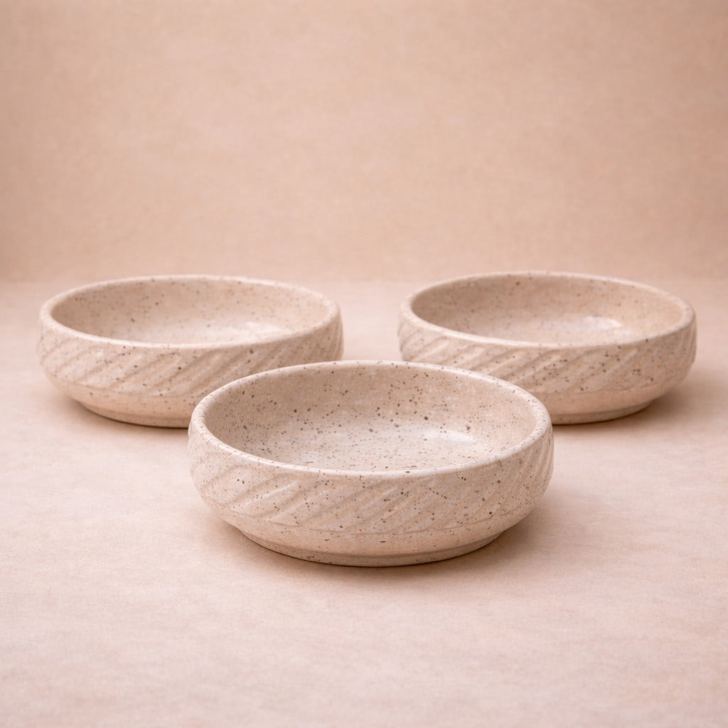 Three ceramic bowls with textured surface on a beige background
