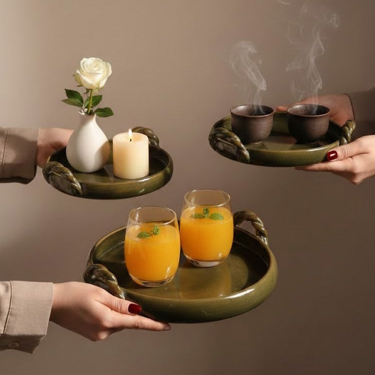 Three trays being held by hands, each with a white rose, candles, and glasses of orange juice.