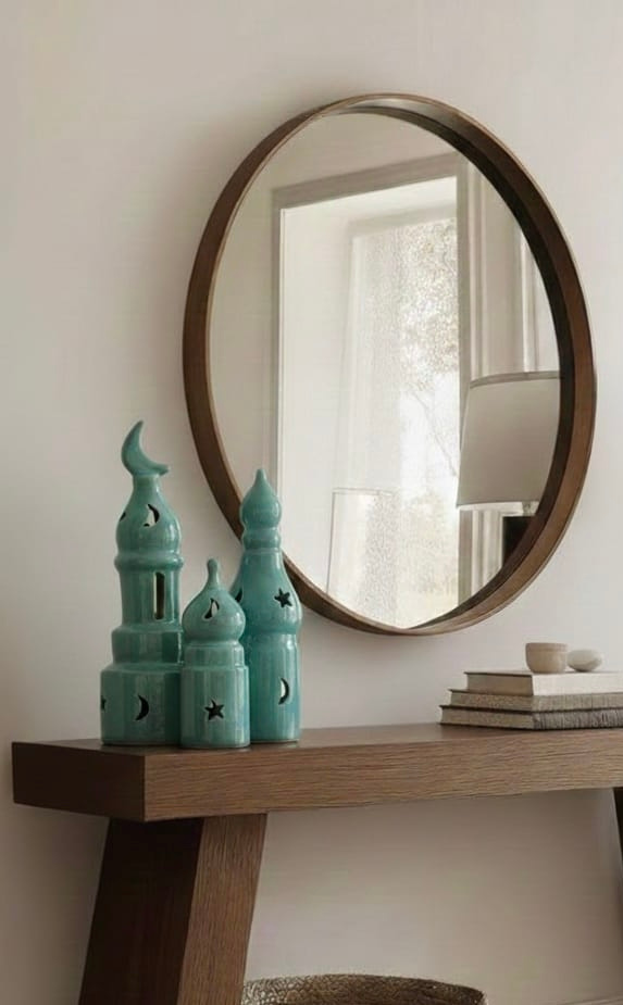 Round wooden-framed mirror on a wall above a wooden console table with decorative items.